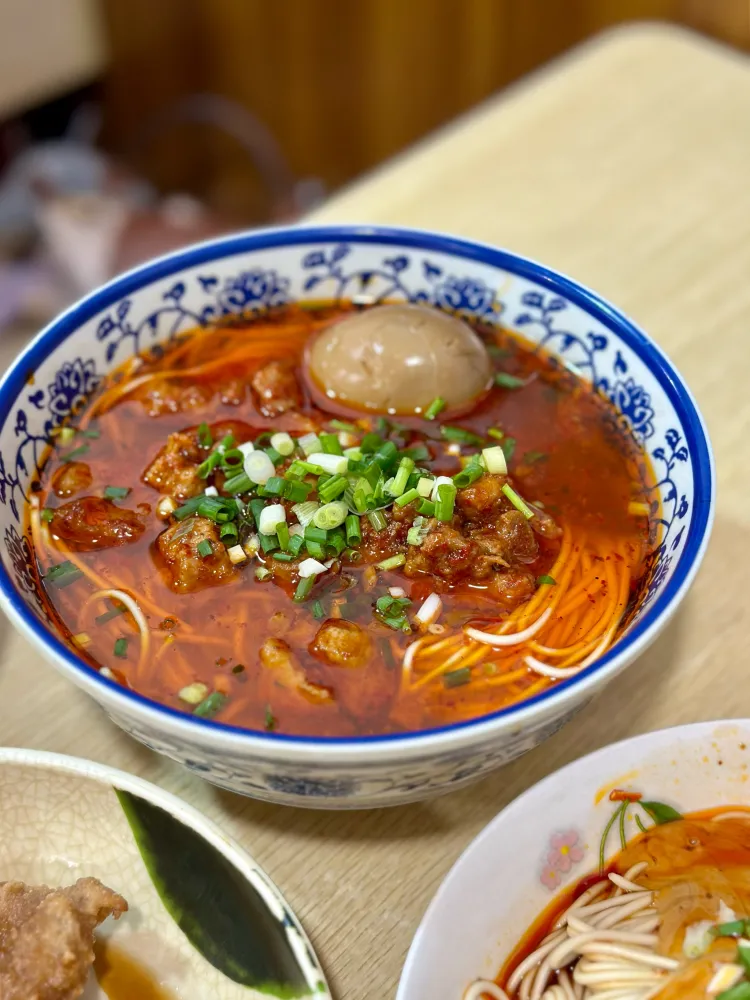 A Shanghai noodle counter with handwritten order slips clipped above the broth pots