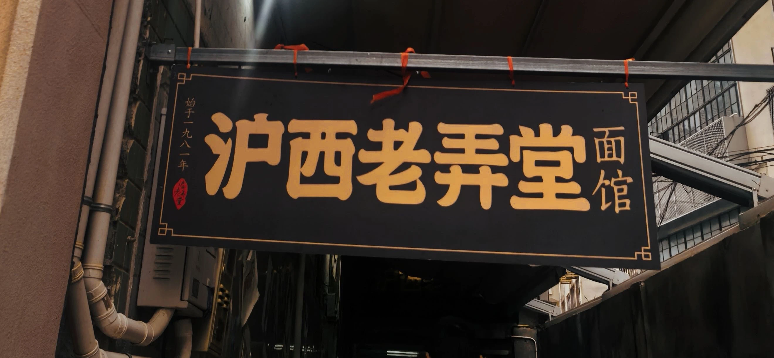 The black-and-gold Huxi Old Longtang Noodle House sign in the lane